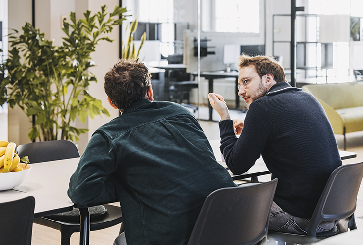 Two colleagues seated together in discussion, exchanging ideas in a collaborative workspace.