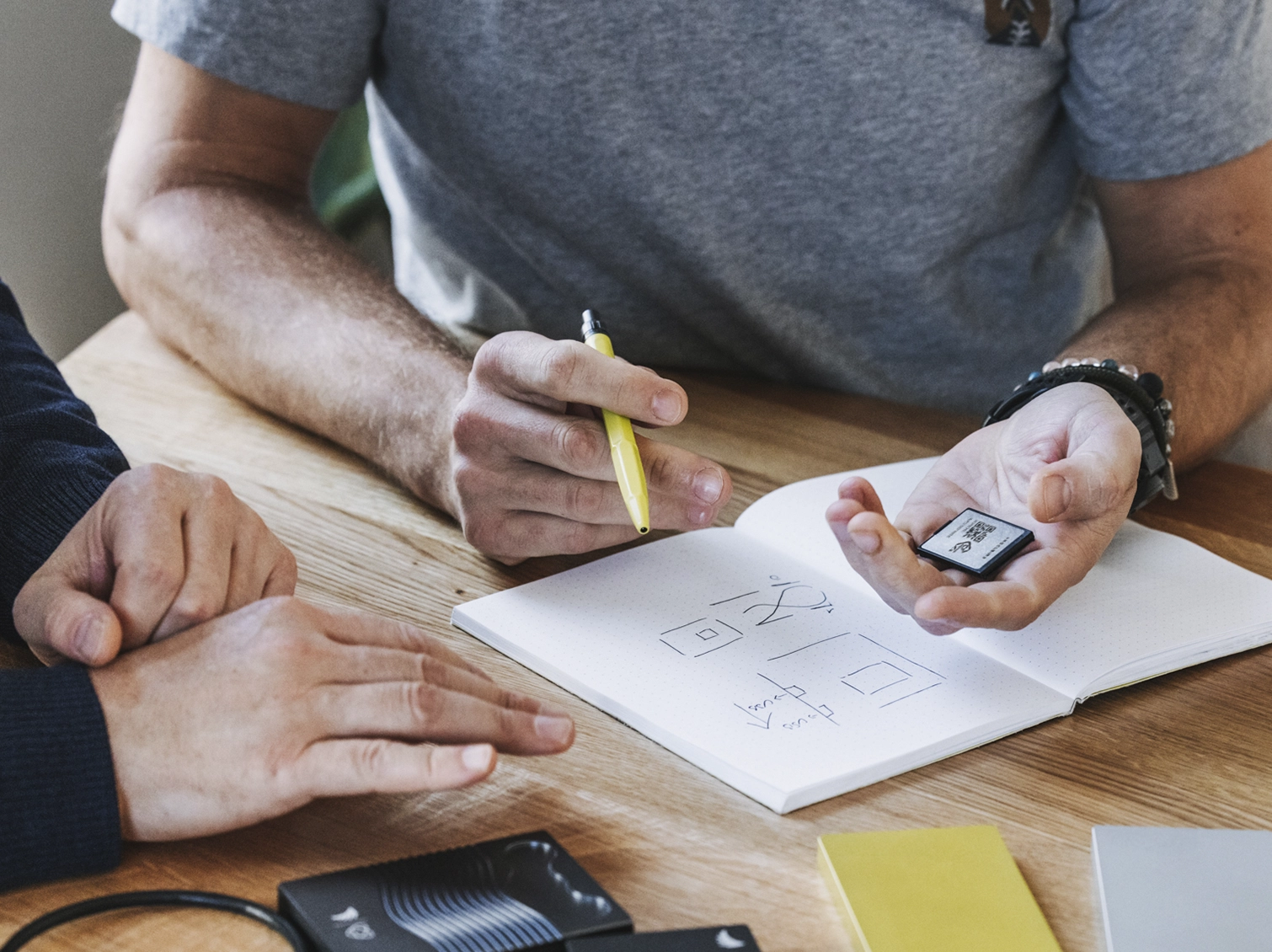 Close-up of a person writing sketches of a memory card on a notebook, symbolizing Angelbird's design and development process.